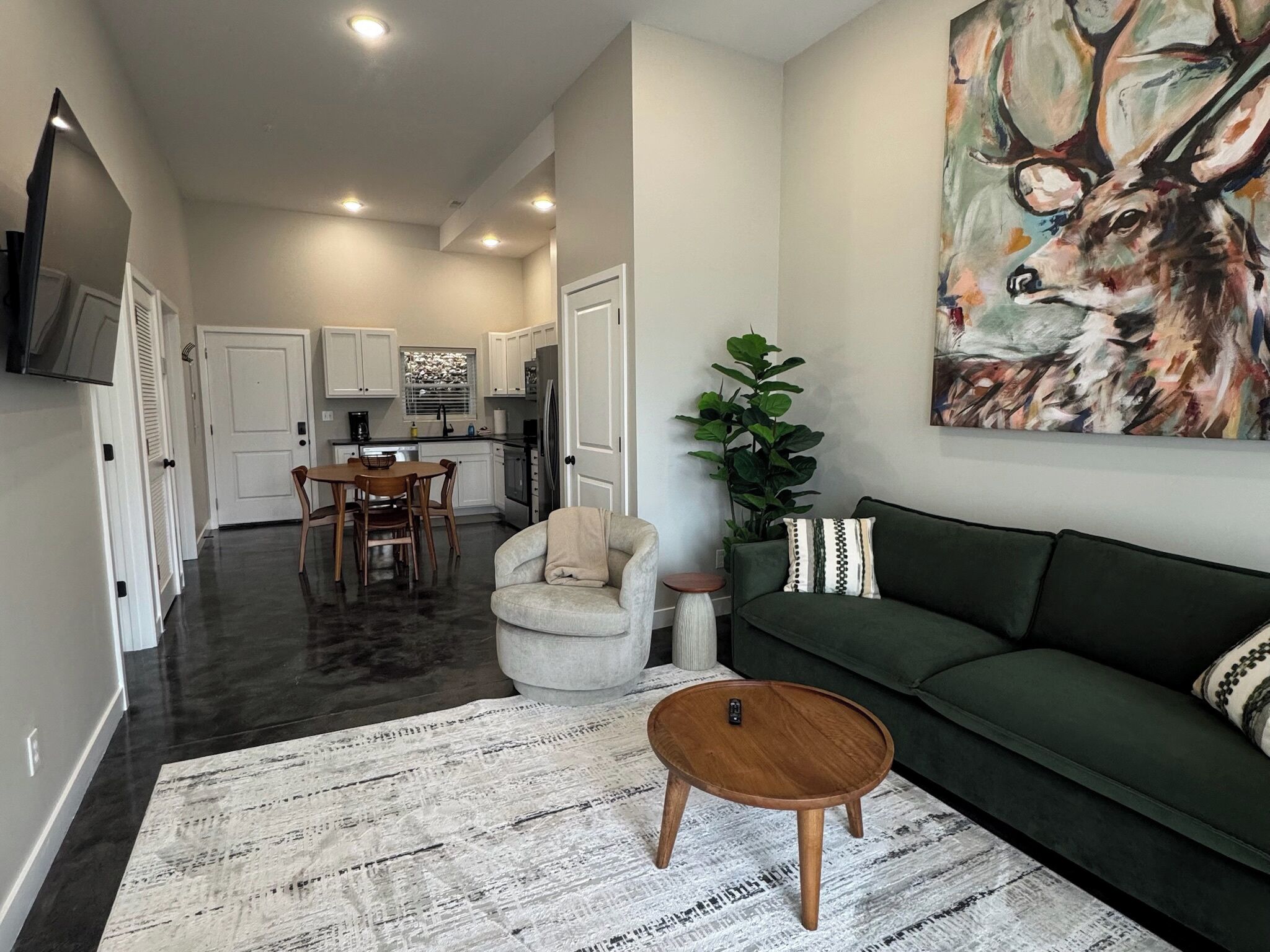 Un salon moderne avec un canapé vert, une table basse ronde et un tableau représentant un cerf.