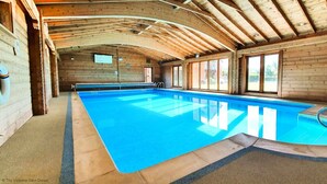 Un'ampia piscina coperta con pareti in legno e un soffitto alto.