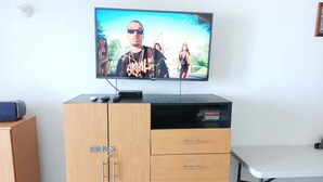 A television on a wooden cabinet with a remote control, a keyboard, and a small speaker. - Loft with ocean view! "Twin Towers Tres Mares" (Acapulco de Juárez)