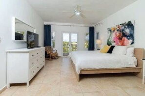 Ein modernes Schlafzimmer mit Bett, Kommode, Fernseher und Deckenventilator.