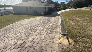 A paved driveway leading to a house with a grey roof and an American flag.