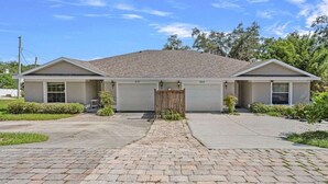 A two-story house with a garage, a paved driveway, and a wooden gate.