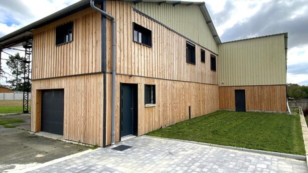 A modern building with a wooden facade, multiple windows, and a flat roof.