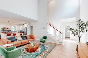 A spacious living area with a sofa, chairs, a coffee table, and a staircase leading to another level. - Savannah Retreat | Private Spa | 6 min to Downtown (Savannah)