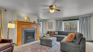 Una sala de estar con chimenea, ventilador de techo, sofá y alfombra.