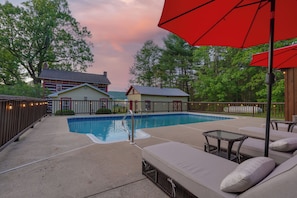 A backyard with a swimming pool, outdoor furniture, and a red umbrella. - Laurel Haven | Private Pool + Fireplace (Rebersburg)