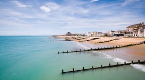 A coastal town with a sandy beach, a wooden jetty, and buildings along the shore. - Luxury Beachfront Retreat for 14 With Hot Tub (Bognor Regis)