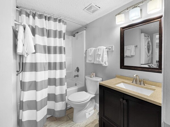 Baño con cortina de ducha, inodoro, lavamanos y espejo.