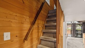 A wooden interior with a carpeted staircase leading to a glass door. - Young at Heart Chalet, Pet Friendly- 507 (Crescent Lake Junction)