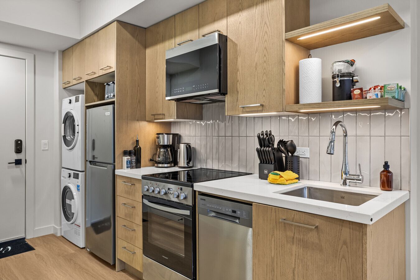 A modern kitchen with built-in appliances, a microwave, a coffee maker, and a sink with a faucet.