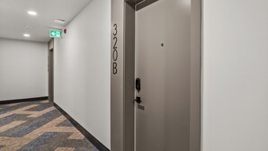 Un couloir doté d’un sol recouvert de moquette, une porte portant l’inscription « 320B » et un panneau indiquant la sortie de secours.
