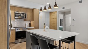 A modern kitchen with a central island, stainless steel appliances, and pendant lighting. - “The Ascent Mountain Haven” (Canmore)