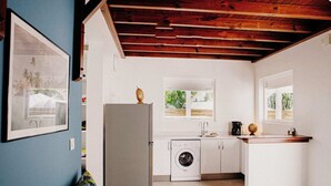 Cocina pequeña con lavadora, lavaplatos y ventana.