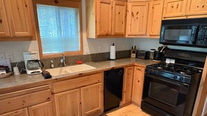Una cocina con armarios de madera, lavavajillas, estufa y microondas.