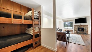 A room with a bunk bed, a fireplace, a TV, and a dining area. - Discovery 4 111:Near Canyon Lodge, Dog Friendly (Mammoth Lakes)