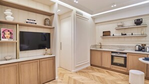 A modern kitchen with wooden cabinets, a built-in oven, and a large flat-screen TV. - Suite Air-conditioned Opera-louvre-2 Bedrooms (Paris)