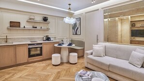 A modern kitchen with wooden cabinets, a dining table, and a sofa in a living area. - Suite Air-conditioned Opera-louvre-2 Bedrooms (Paris)