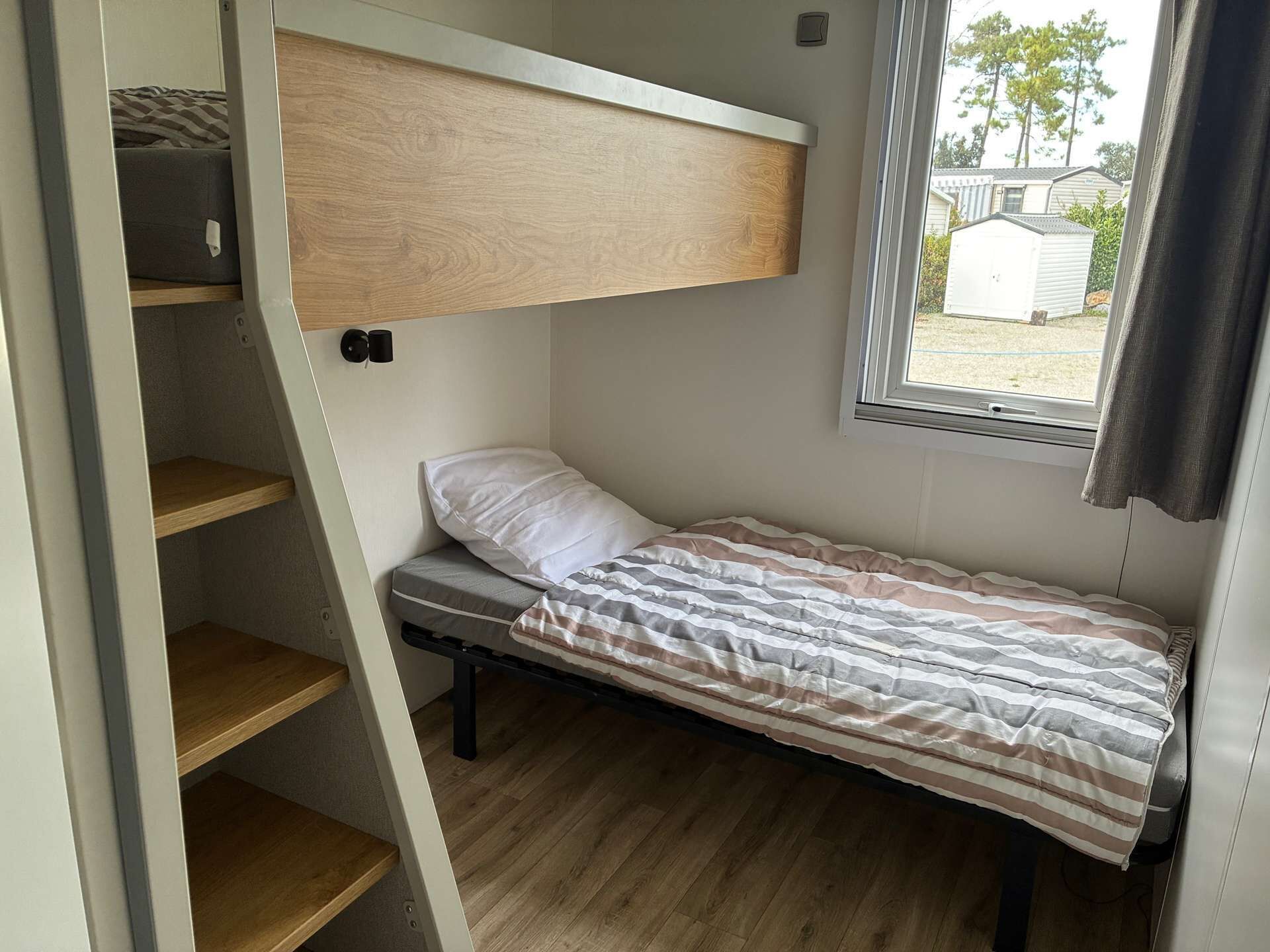 Habitación pequeña con literas, una cama individual, una ventana y vistas al exterior.