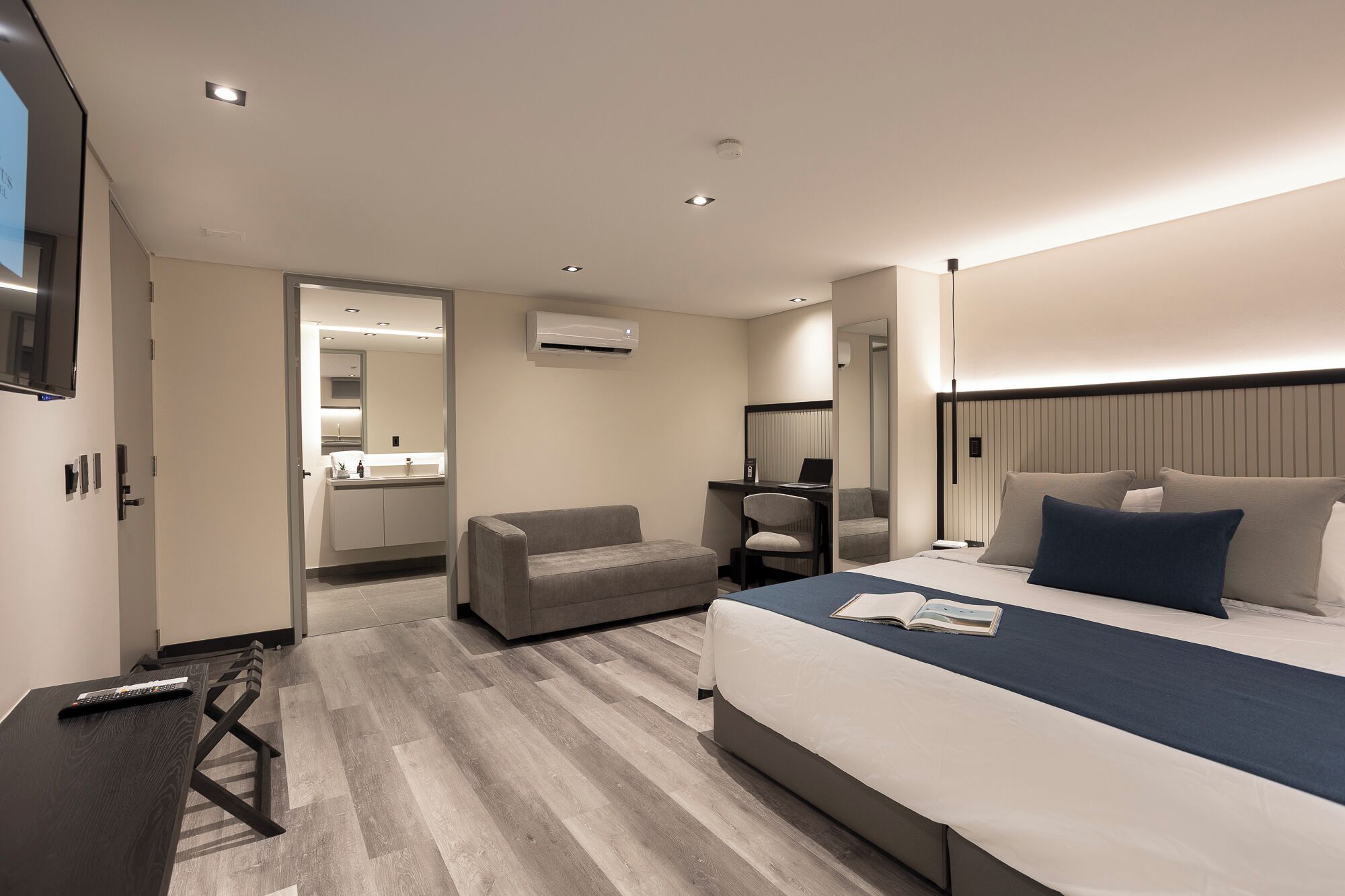 A modern hotel room with a large bed, a desk, a chair, and a TV.