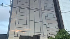En moderne bygning med en spejlbilledeglas facade, hvor ordet "ALTUS" er tydeligt vist øverst.