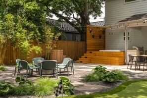 Un jardin avec une terrasse en bois, un espace salon extérieur et un coin barbecue.
