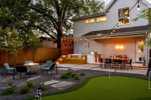 A backyard with a fire pit, outdoor seating, a grill, and a putting green. - Urban retreat w/Spa, Movie, Mini-Golf in DT/6th St (Austin)