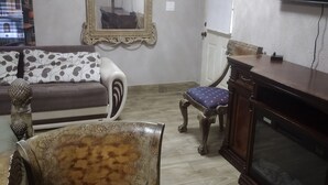 Ein Wohnzimmer mit Sofa, Sessel, Fernseher und Kamin.