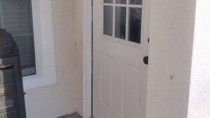 Eine weiße Tür mit Fenster, einem Briefkasten und einem an der Wand befestigten Laternenaufsatz.