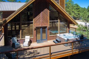A wooden cabin with a deck, hot tub, and two chairs. - Pah's Haus | Hot Tub | Scenic View | Dog-Friendly (Angel Fire)