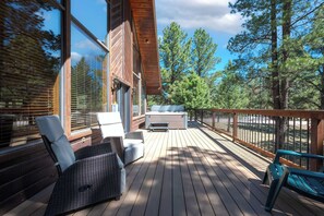A wooden deck with outdoor furniture, a hot tub, and a view of trees. - Pah's Haus | Hot Tub | Scenic View | Dog-Friendly (Angel Fire)