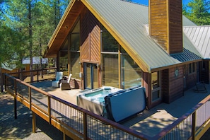 Een houten hut met een terras, een hottub en een groot raam.