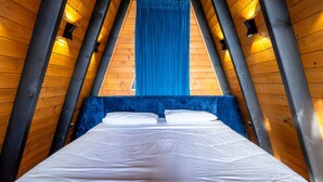 A room with a high ceiling, wooden beams, a bed with white linens, and a blue curtain. - Blue Retreat The Golden Cabins With Garden (Gjinar)