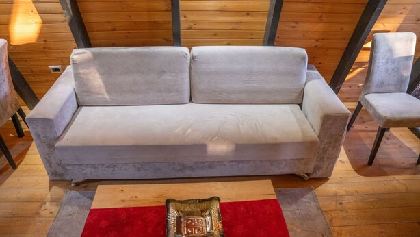 A white sofa with two cushions in a room with wooden walls and a red rug. - Grey Retreat The Golden Cabins With Garden (Gjinar)