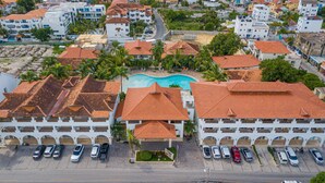 A residential area with two-story buildings, a swimming pool, and a parking lot. - Luxury 1BR Paraiso Bayahibe · Pool · Beach · AC · Kitchen (Bayahíbe)