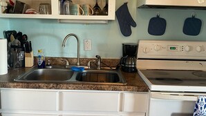 A kitchen with a sink, stove, and cabinets. - Welcome to The Crow's Nest at Fisherman's Wharf, a cozy waterfront 1 bedroom. (Cedar Key)