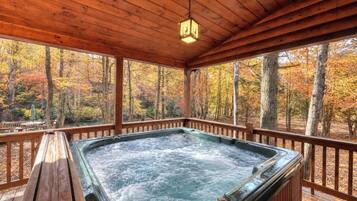 A hot tub in a wooden gazebo with a view of autumn trees.