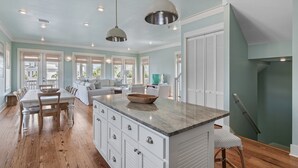 A spacious kitchen with a large island, white cabinetry, and pendant lighting. - EZ Walk 2 Beach! Private Pool, LSV, FirePit, & Bikes! Pet Friendly! (Santa Rosa Beach)