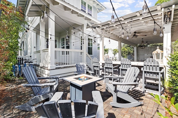 A covered outdoor seating area with Adirondack chairs and a fire pit. - Outdoor Oasis! Walk 2 Shops & Eat! LSV/Golf Cart, 3 Kings & Bikes! (Santa Rosa Beach)