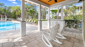 A covered outdoor area with a pool, white rocking chairs, and a ceiling fan. - Outdoor Oasis! Walk 2 Shops & Eat! LSV/Golf Cart, 3 Kings & Bikes! (Santa Rosa Beach)