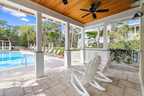 A covered outdoor area with a pool, white rocking chairs, and a ceiling fan. - Outdoor Oasis! Walk 2 Shops & Eat! LSV/Golf Cart, 3 Kings & Bikes! (Santa Rosa Beach)