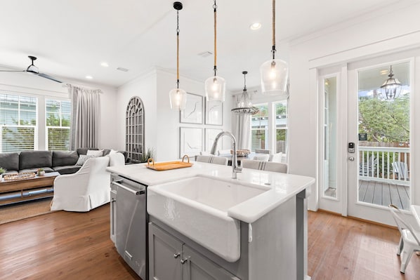 A modern kitchen with a large island, pendant lights, and a view to the outside. - Outdoor Oasis! Walk 2 Shops & Eat! LSV/Golf Cart, 3 Kings & Bikes! (Santa Rosa Beach)