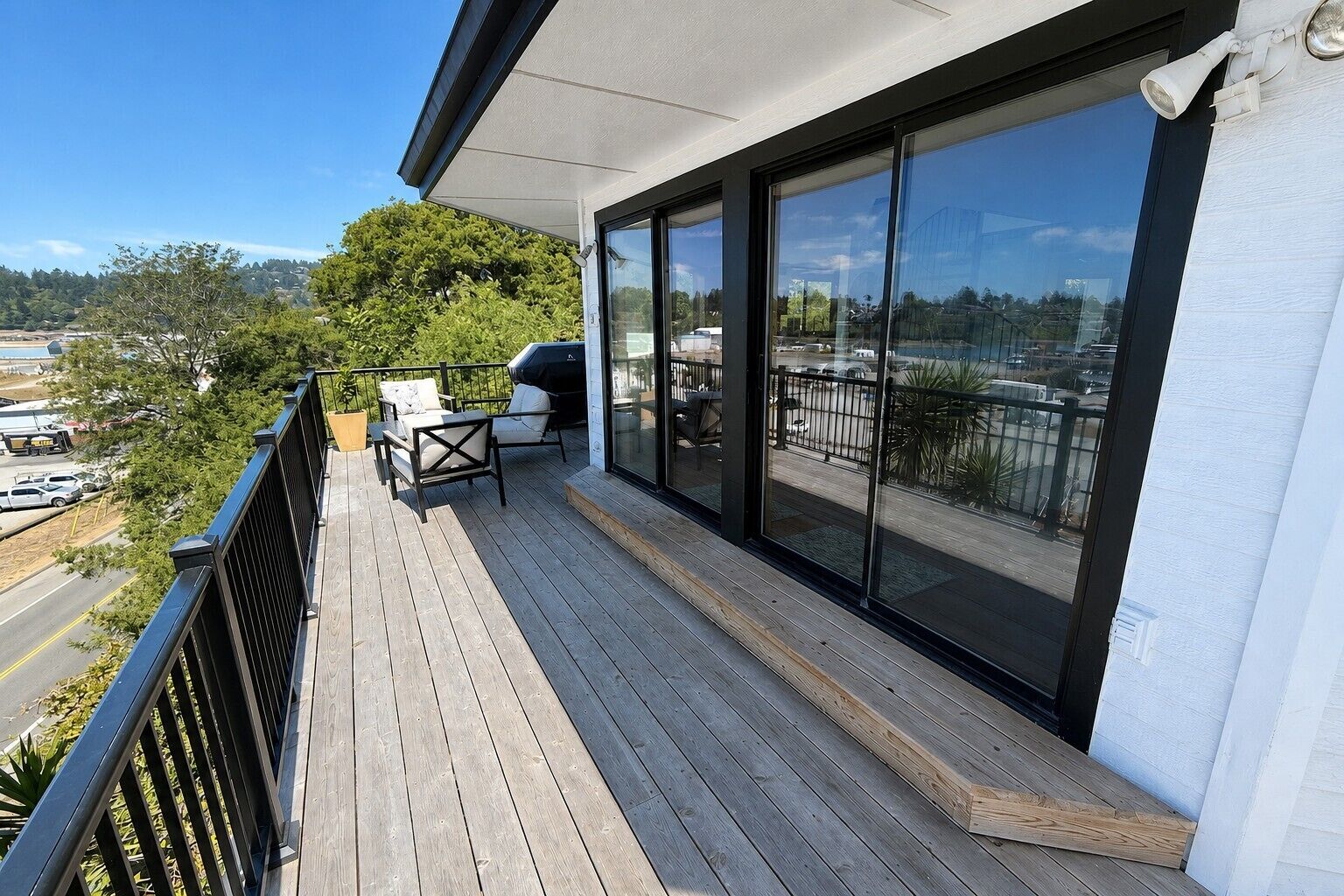 A balcony with a view of a parking area and trees.