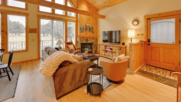 A spacious living room with a fireplace, wooden beams, large windows, and a cozy seating area. - Game Room & 5 Pools: Chalet at Eagle Crest Resort (Redmond)