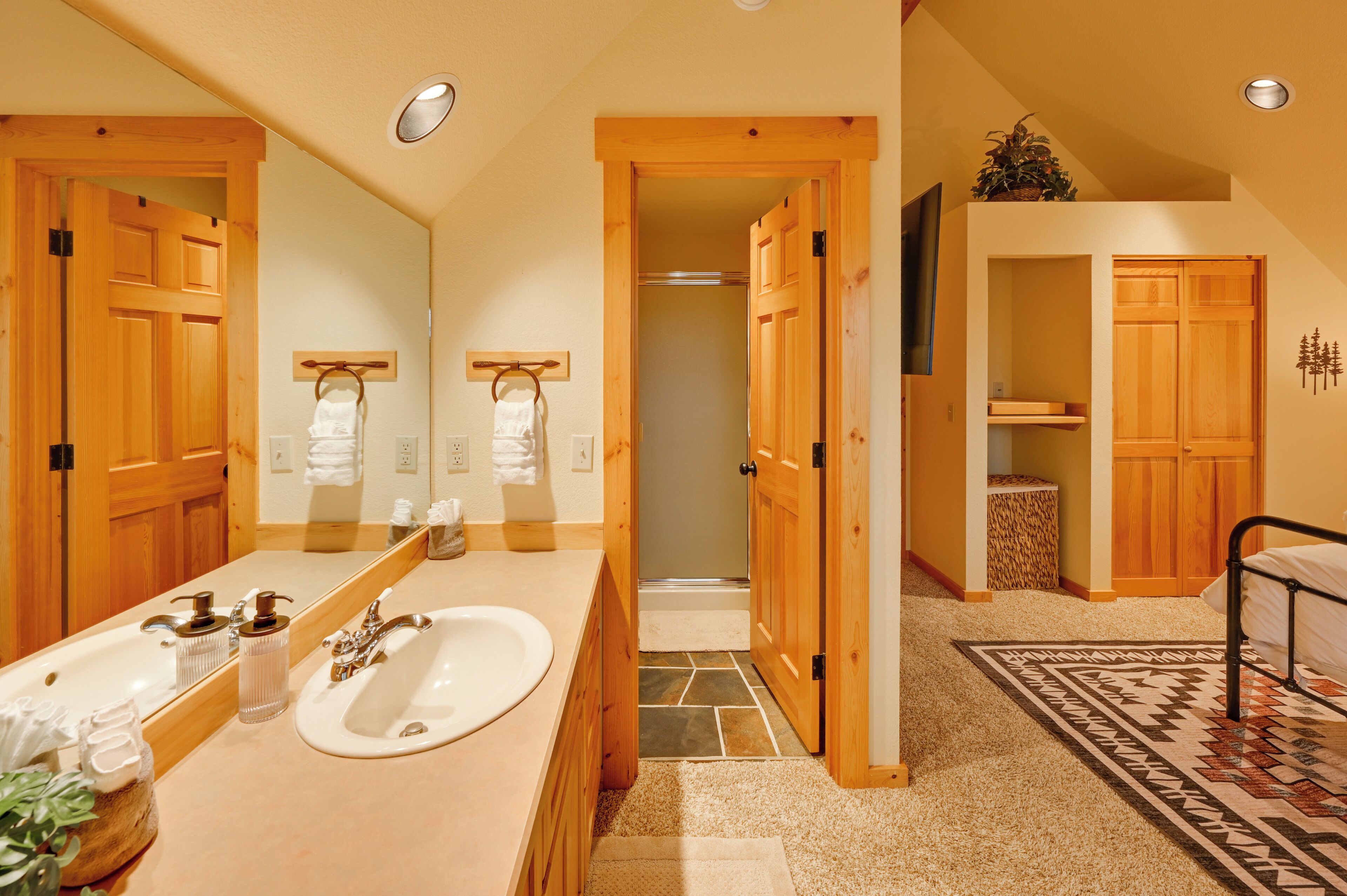 Une salle de bain moderne avec un grand miroir, des meubles en bois, un lavabo et un espace douche.