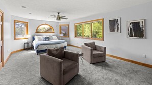 Ein geräumiges Schlafzimmer mit einem großen Bett, zwei Sesseln, einem Deckenventilator und Kunstwerken an den Wänden.