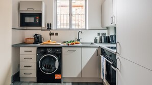 Une cuisine compacte équipée d’un lave-linge intégré, d’un four à micro-ondes et d’un évier.