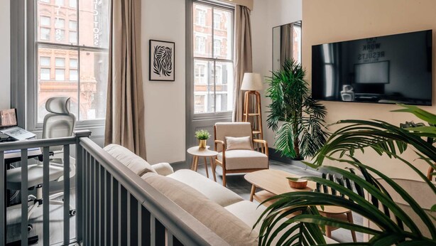 Un salon moderne comprenant un canapé, des fauteuils, un téléviseur et une table à manger.