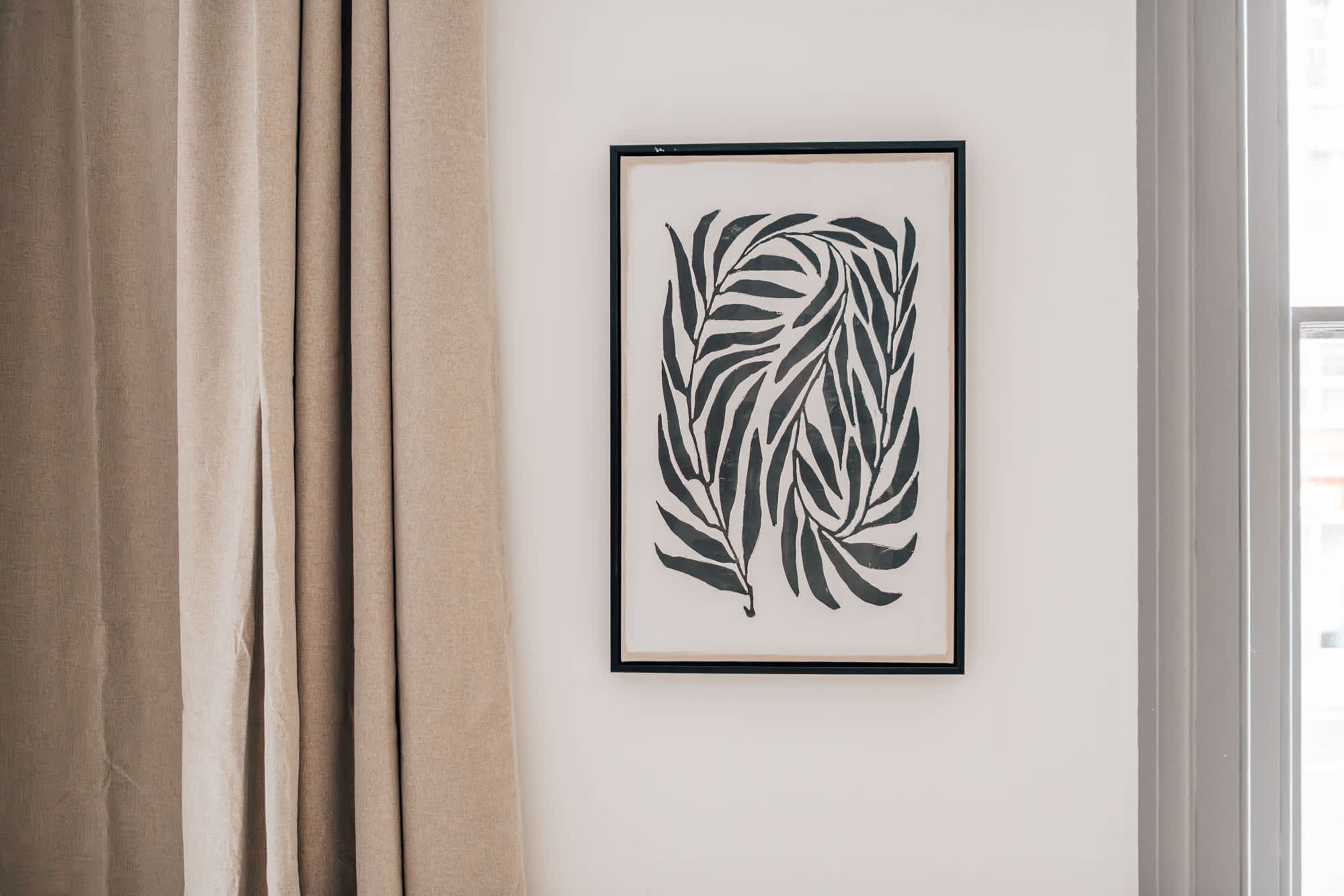 Eine gerahmte Schwarz-Weiß-Blatt-Kunstwerk an einer weißen Wand.
