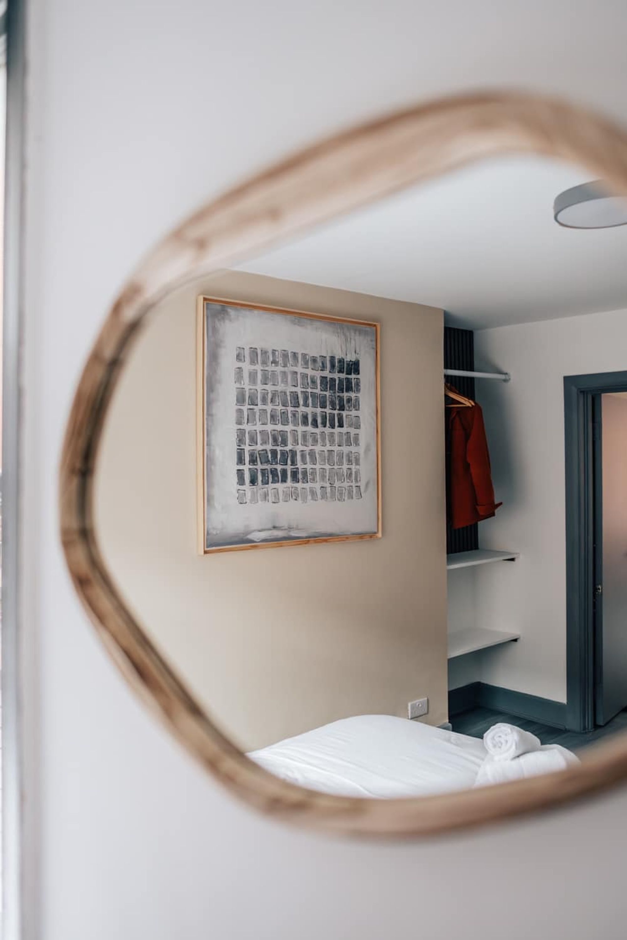 Ein Schlafzimmer mit einem Bett, einem gerahmten Bild an der Wand, einem Schrank mit Regalen und einer Tür.