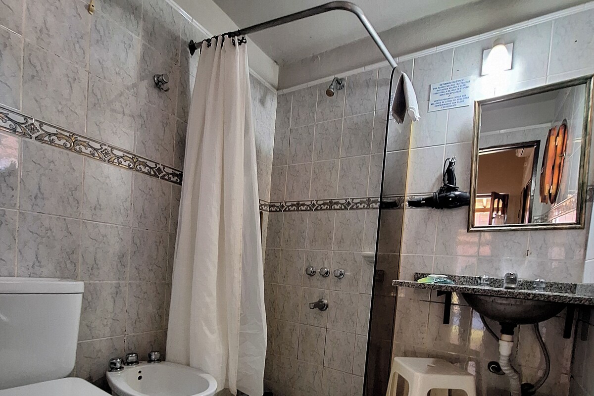 A bathroom with a toilet, bidet, shower, and sink.